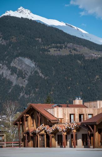 a building with a snow covered mountain in the background at Hotel Base Camp Lodge - Bourg Saint Maurice in Bourg-Saint-Maurice