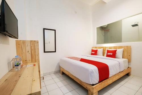 um quarto com uma cama e uma televisão de ecrã plano em OYO 2041 Griya Aneka em Yogyakarta