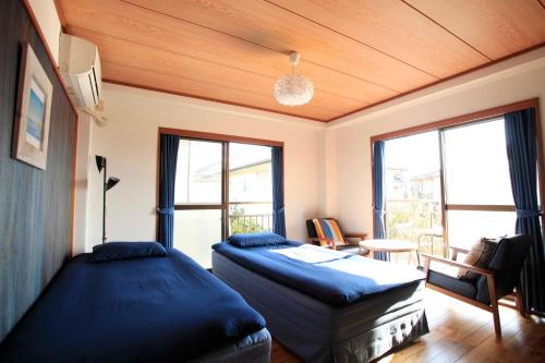 a bedroom with two beds and a table and windows at 一棟貸しの海宿 Kamakura SUN&BREEZE in Kamakura