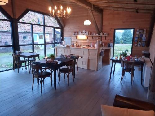 a kitchen and dining room with tables and chairs at Pipowagen Lidewei Groningen Westerwolde unieke ligging met eigen tuin en vrij uitzicht over veld naar natuurgebied in Onstwedde