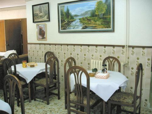 un comedor con 2 mesas y sillas y una pintura en Hotel La Parra, en Archena