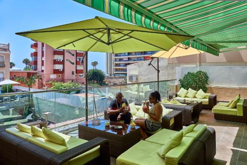 people sitting at tables under umbrellas at Hotel Soho Boutique El Tiburon & Spa -Adults Recommended in Torremolinos
