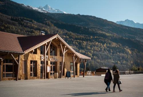 two women walking in front of a building with a mountain at Hotel Base Camp Lodge - Bourg Saint Maurice in Bourg-Saint-Maurice