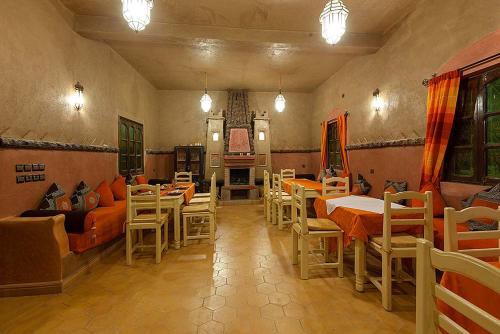 a living room with tables and chairs and a couch at Riad Dar Ouzine in Merzouga