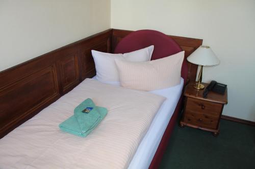 a bed with a green towel sitting on top of it at Hotel garni Am Dippeplatz in Quedlinburg