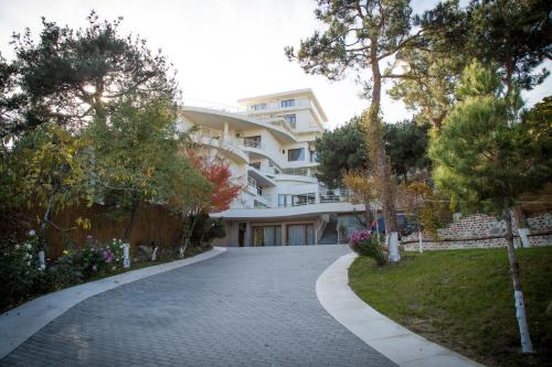 a driveway leading to a large white building at Hotel Beaumonde Garden in Tbilisi City
