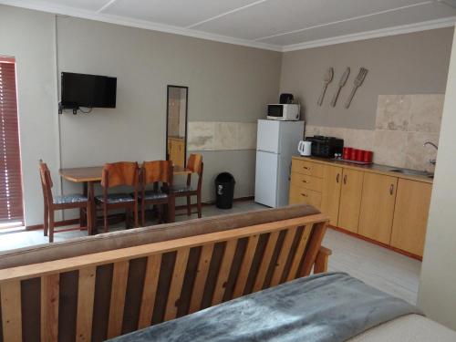 a kitchen with a table and chairs and a refrigerator at La Paix Guesthouse in Beaufort West