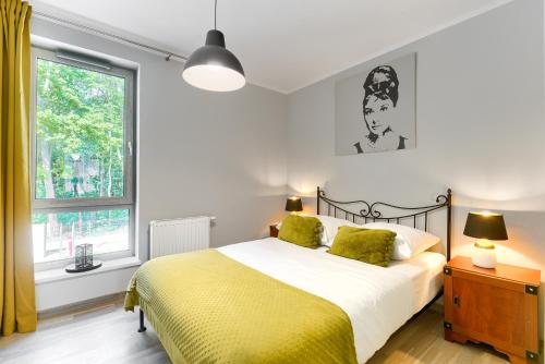 una camera da letto con un letto con lenzuola gialle e una finestra di Apartament Bursztynowy Rezydencja Park a Mielno