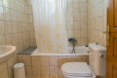 a bathroom with a toilet and a shower curtain at Bratis Apartments in Keri