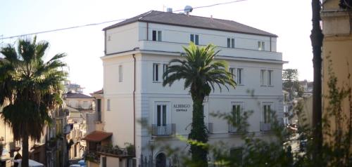 a white building with a palm tree in front of it at Albergo Centrale in Lamezia Terme