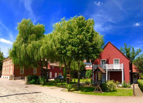 a tree in front of a red house at Pension Auf der Tenne in Klöden