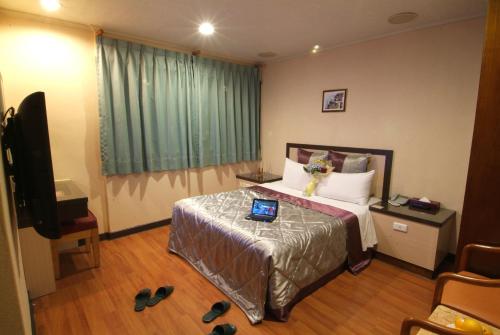 a bedroom with a bed with a laptop on it at Left Bank Hotel in Hsinchu City