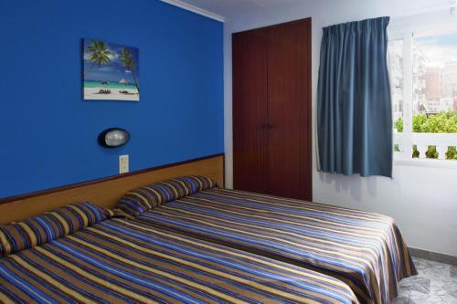 a bedroom with a bed with a blue wall at Europa Family Apartments in Blanes
