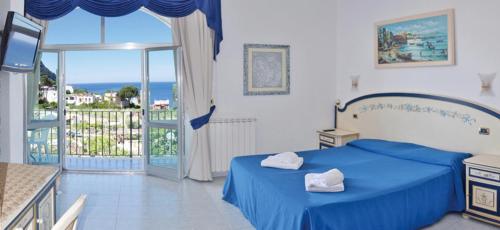 a bedroom with a blue bed and a balcony at Hotel Villa Cimmentorosso in Ischia