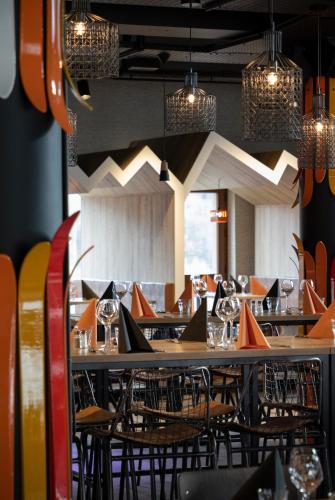 a dining room with tables and chairs and lights at Hotel Base Camp Lodge - Bourg Saint Maurice in Bourg-Saint-Maurice