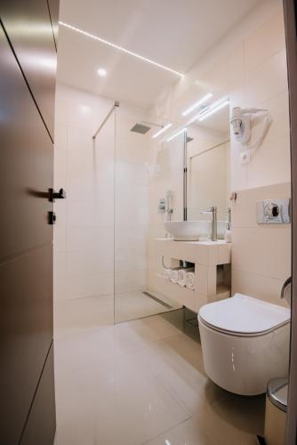 a white bathroom with a toilet and a sink at Mountain Paradise & Wellness in Izvoare