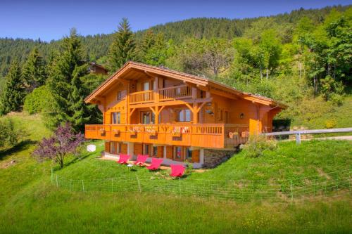 a large wooden house on a hill with pink chairs at Chalet Tekoa - OVO Network in Manigod