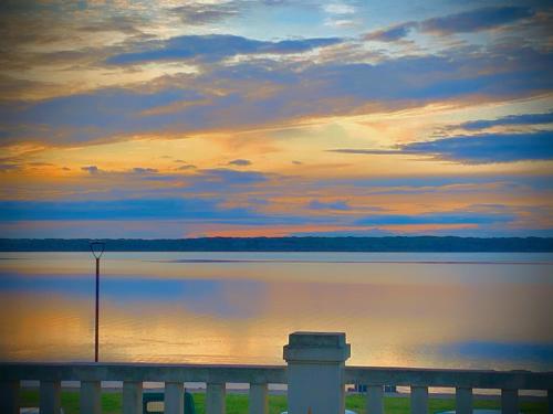 a sunset over a body of water with a dock at Hotel Relais I Presidi in Orbetello