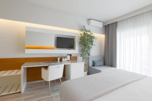 a bedroom with a bed and a desk and a tv at San Panteleimon in Paralia Panteleimonos