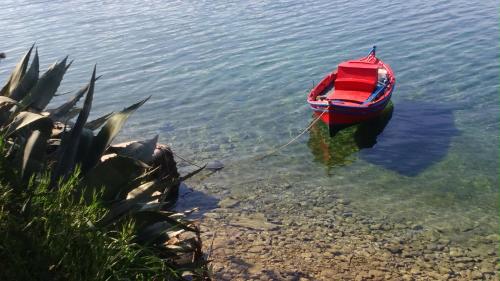 a red boat in the water next to the shore at Haus Pigadi in Pteleós