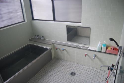 a bathroom with a bath tub and a mirror at Minshuku Iwaki in Fujikawaguchiko