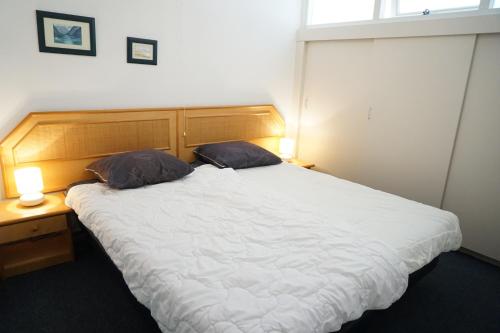 een slaapkamer met een groot wit bed met 2 kussens bij Strandslag Juliana 181 in Julianadorp
