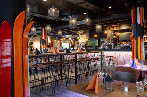 a restaurant with a bar with chairs and surfboards at Hotel Base Camp Lodge - Bourg Saint Maurice in Bourg-Saint-Maurice