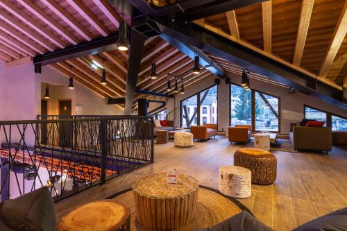 a large lobby with tables and chairs and windows at Hotel Base Camp Lodge - Bourg Saint Maurice in Bourg-Saint-Maurice