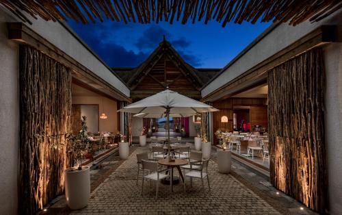 a restaurant with tables and umbrellas on a patio at Preskil Island Resort in Blue Bay