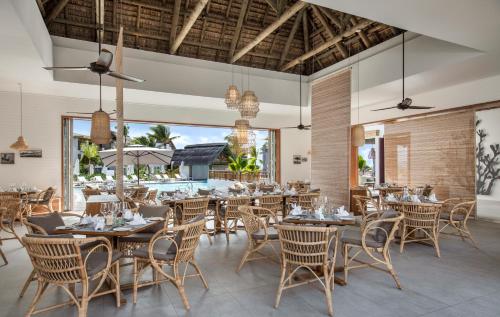 a dining room with tables and chairs and a patio at Preskil Island Resort in Blue Bay