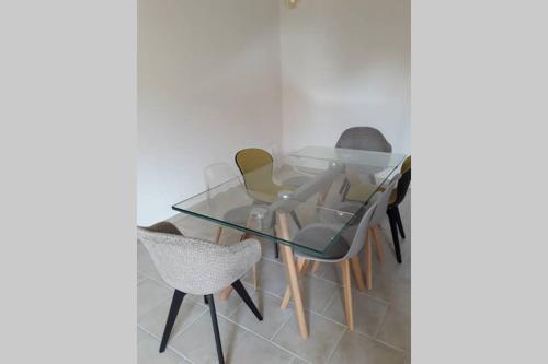 a glass table with four chairs around it at Maison en pierre totalement renovée in Marsainvilliers