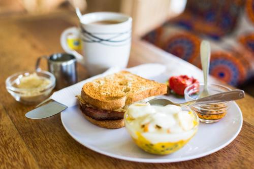 a plate of food with a sandwich and a cup of coffee at Distant Relatives Ecolodge & Backpackers in Kilifi