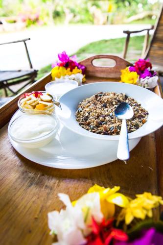 a plate of food on a wooden table with flowers at Distant Relatives Ecolodge & Backpackers in Kilifi