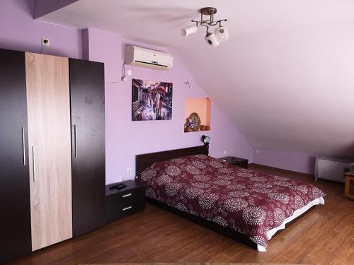 1 dormitorio con cama roja y paredes moradas en Къща Зорница, en Brestovitsa