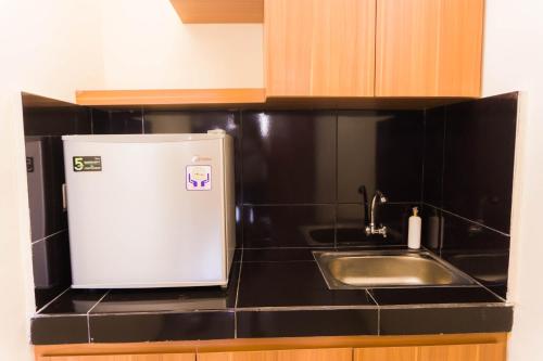 a kitchen with a sink and a small refrigerator at Cakra House in Denpasar