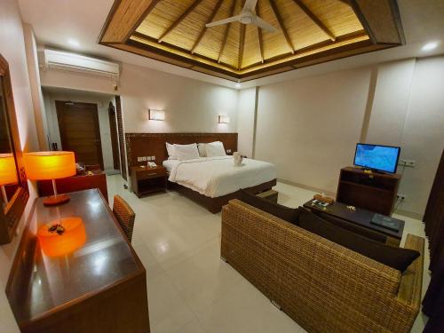 a bedroom with a bed and a couch and a television at Hotel Genggong in Candidasa