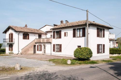 een wit huis met bruine ramen aan een straat bij La Locanda in Calvignano