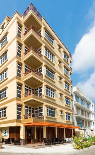 a large apartment building with tables in front of it at Three Inn in Hulhumale