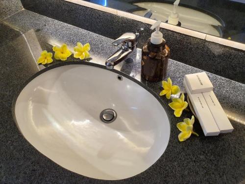 um lavatório de casa de banho com flores amarelas num balcão em Hotel Genggong em Candidasa
