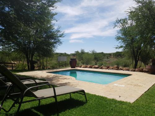 a swimming pool with two lawn chairs in a yard at Weltevreden Game Lodge in Bloemfontein