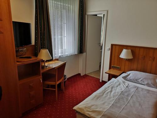 um quarto de hotel com uma cama, uma secretária e uma televisão em Hotel & Ristorante Il Duomo em Olpe