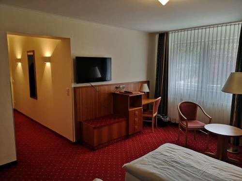 um quarto de hotel com uma cama e uma televisão de ecrã plano em Hotel & Ristorante Il Duomo em Olpe