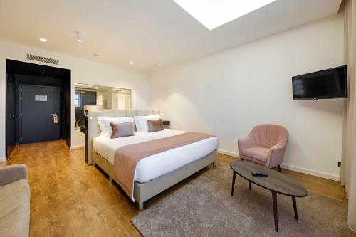 a bedroom with a bed and a tv and a chair at SDivine Fatima Hotel, Congress & Spirituality in Fátima