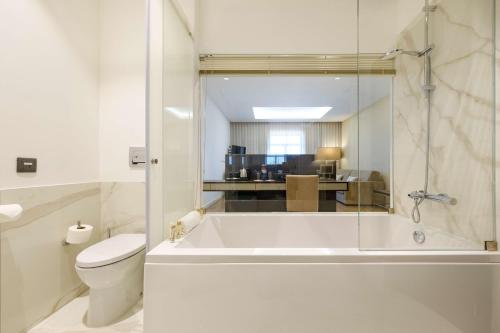 a white bathroom with a tub and a toilet at SDivine Fatima Hotel, Congress & Spirituality in Fátima
