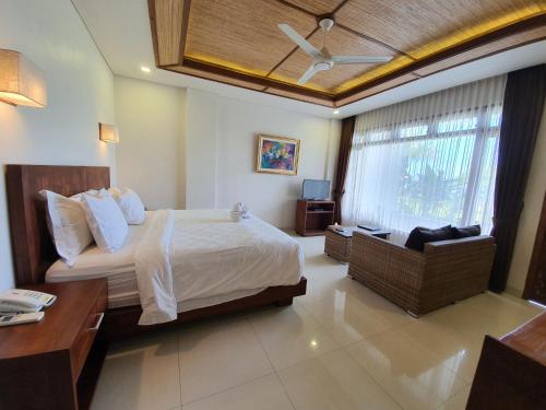 a bedroom with a bed and a desk and a chair at Hotel Genggong in Candidasa