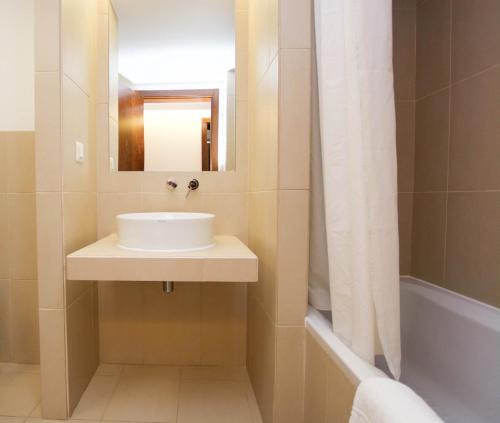 une salle de bains avec lavabo, miroir et baignoire dans l'établissement Salgados, Relax & Fun for family, à Guia
