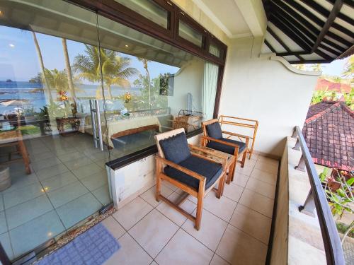 a balcony with chairs and a view of the ocean at Hotel Genggong in Candidasa