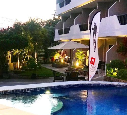 a swimming pool in front of a building at Mayfair Resort in Panglao Island