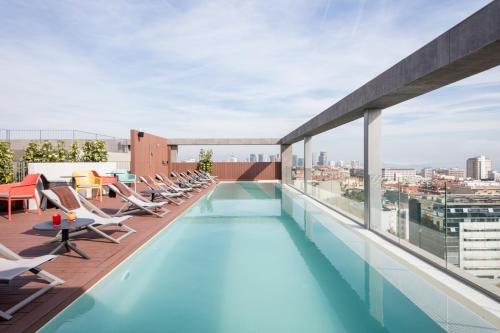 
a pool with a lot of chairs and umbrellas at Acta Voraport in Barcelona
