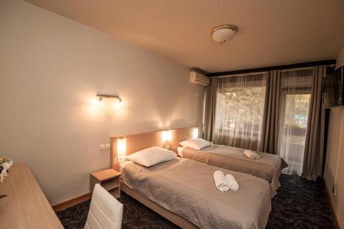 a bedroom with two beds and a table and a window at Hotel Faraon in Celje